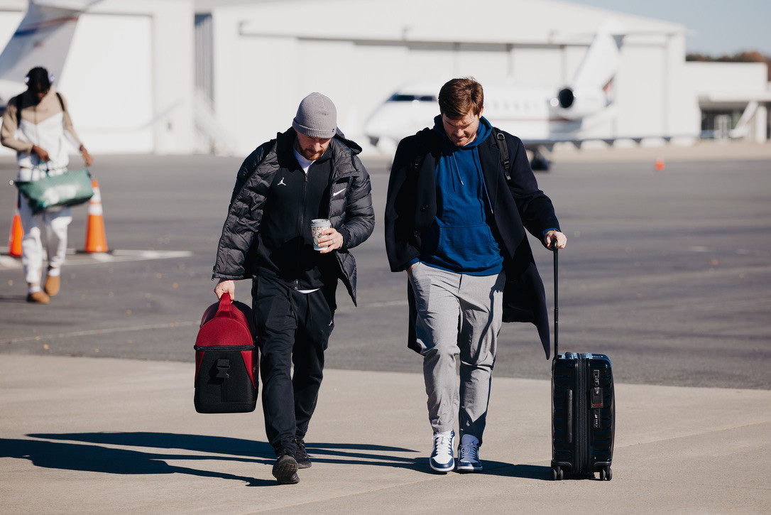 Matt Tuttle walking beside an athlete on an airport tarmac.